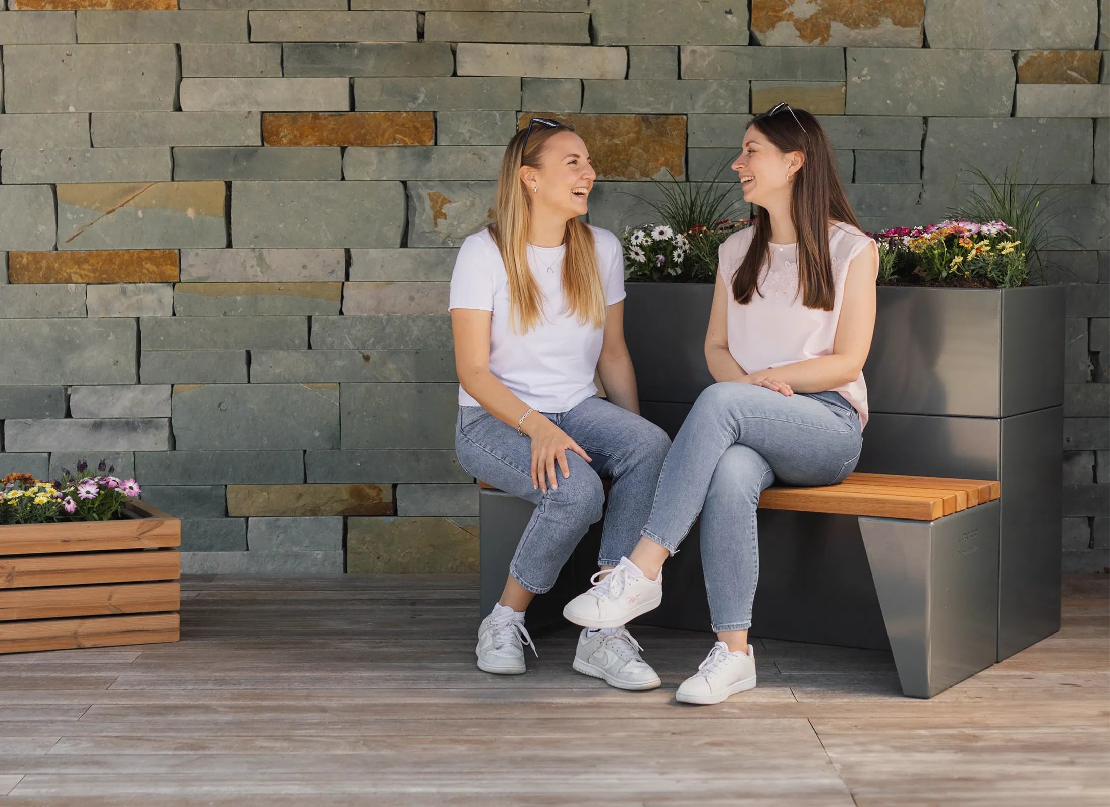 Sitzbank Amara als moderne Outdoor-Bank ohne Rückenlehne mit klarer Formensprache, 5 mm starkem, verzinktem und pulverbeschichtetem Stahlgestell in RAL 7043 und Sitzfläche aus Thermo-Fichte oder Bangkirai.