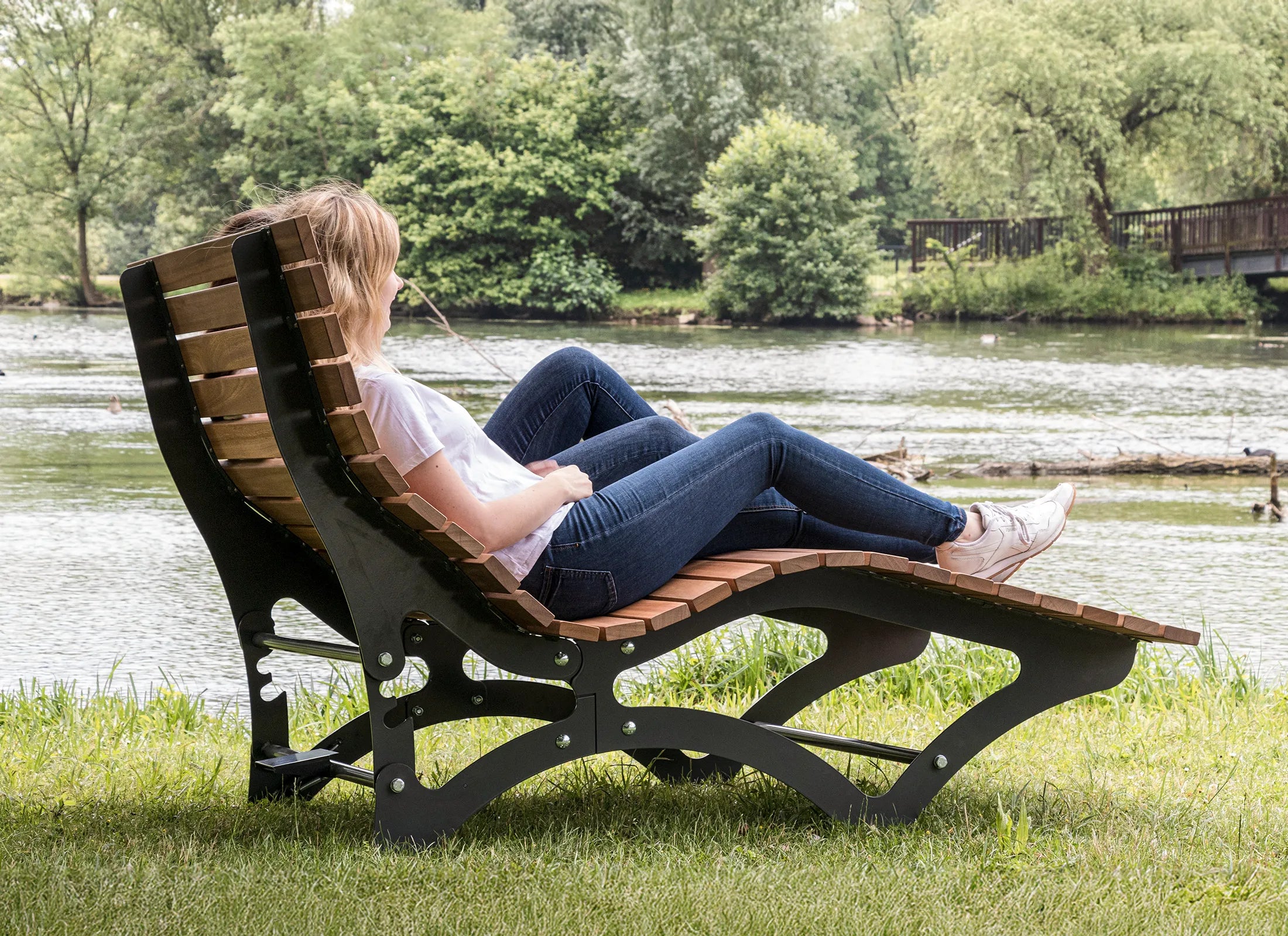 Waldsofa Verstellbar von Liegeland mit verstellbarer Rückenlehne im Einsatz in der Natur, komfortable Doppelliege und Outdoor-Relaxliege mit Personen im Park oder Wald.